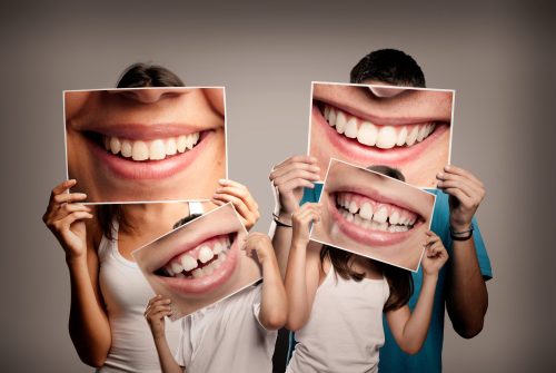 family of four holding pictures of their smiles over their faces